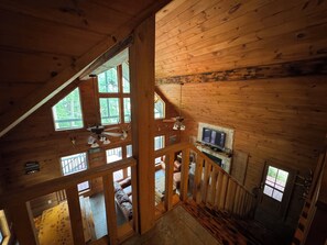 Una cabaña de madera con habitación en el altillo, chimenea y televisor.