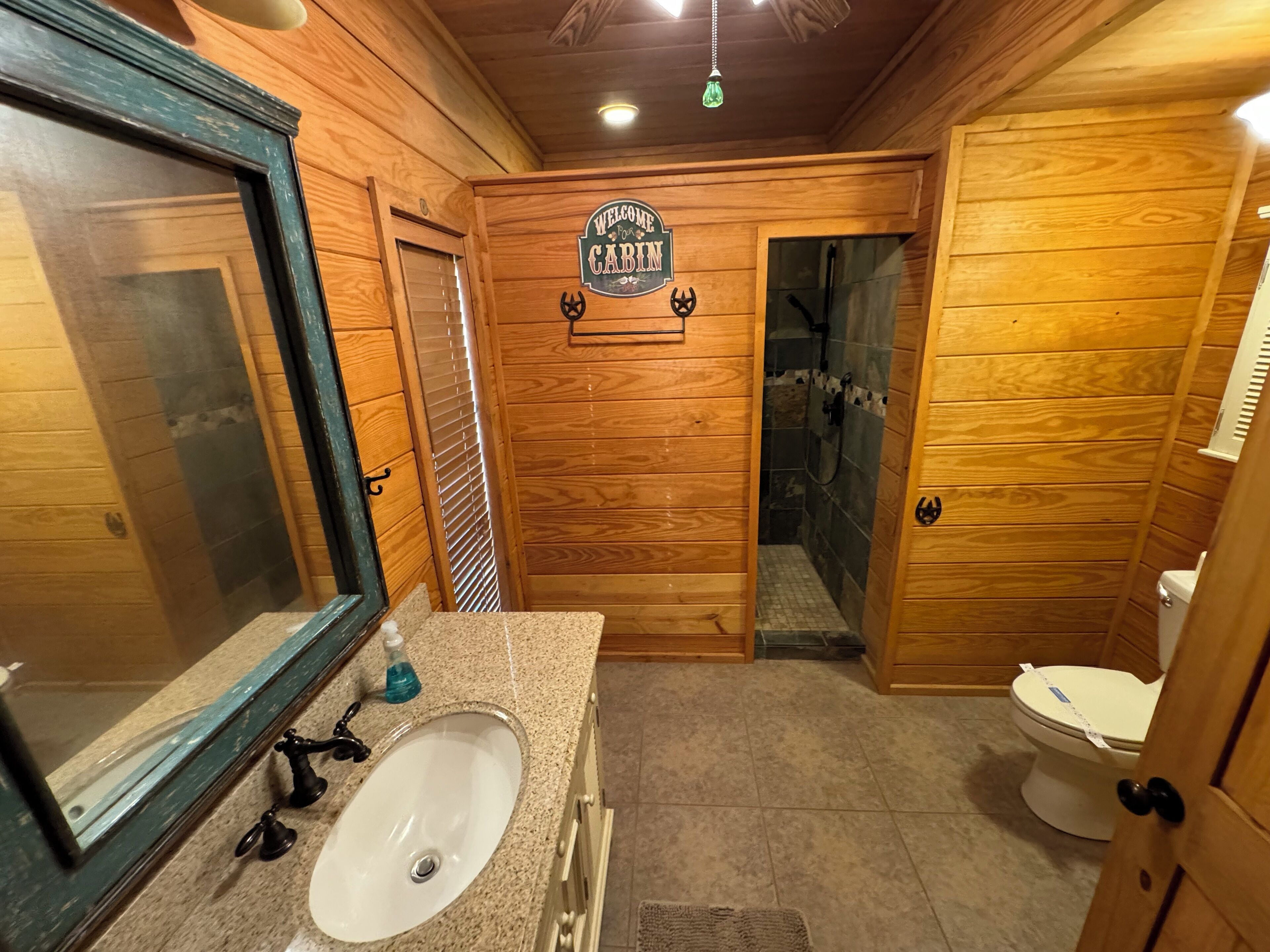 A wooden cabin bathroom with a sink, toilet, and shower.