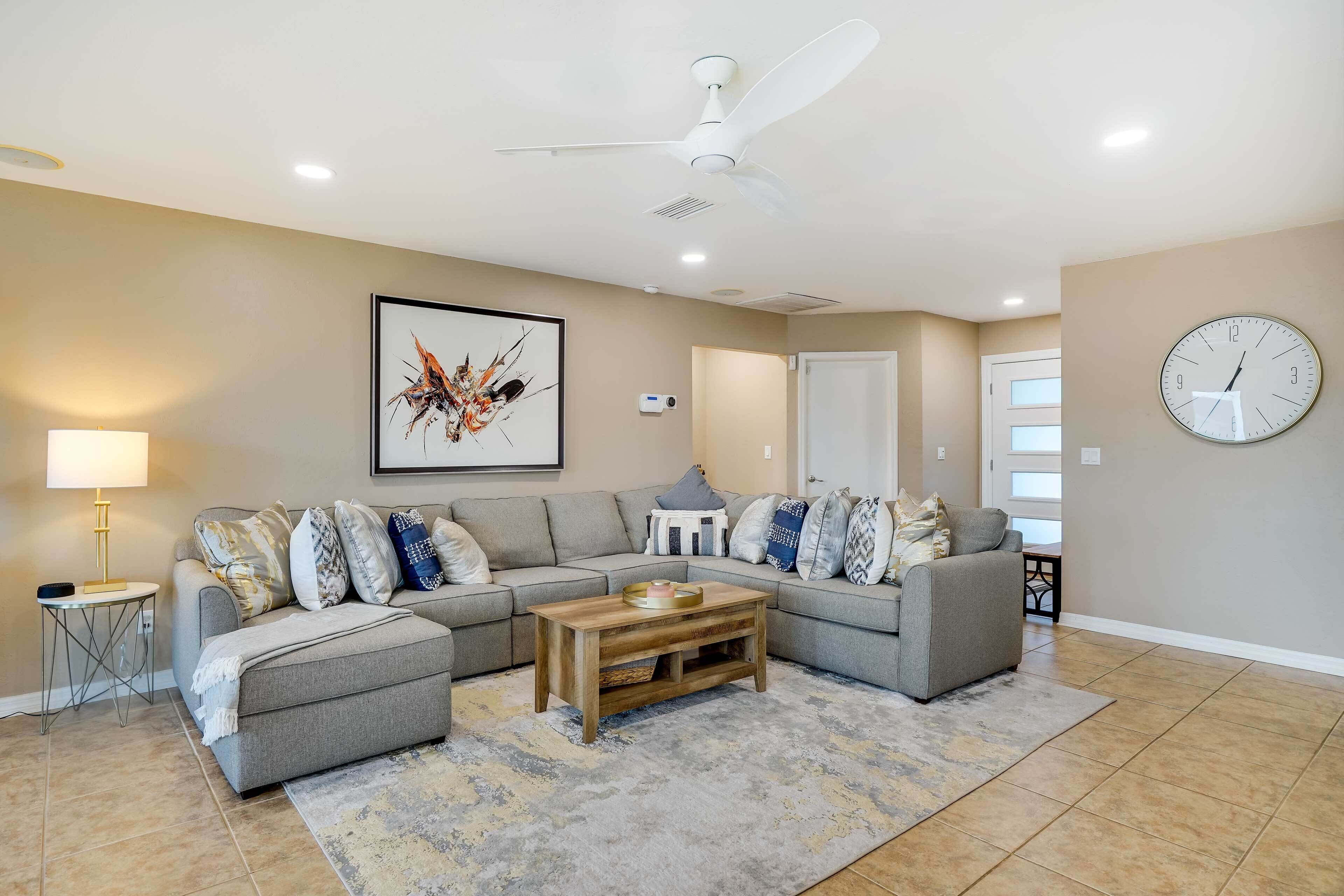 A modern living room with a sectional sofa, a coffee table, a floor lamp, and a ceiling fan.
