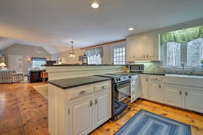 A spacious kitchen with white cabinets, a large island, and a built-in oven. - 1 Mi to Nauset Beach: Upscale Orleans Home w/ Deck (Orleans)