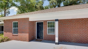 A single-story brick house with a front door, two windows, and a small porch area. - Dog-friendly Pensacola Duplex ~ 7 Mi to Downtown (Pensacola)
