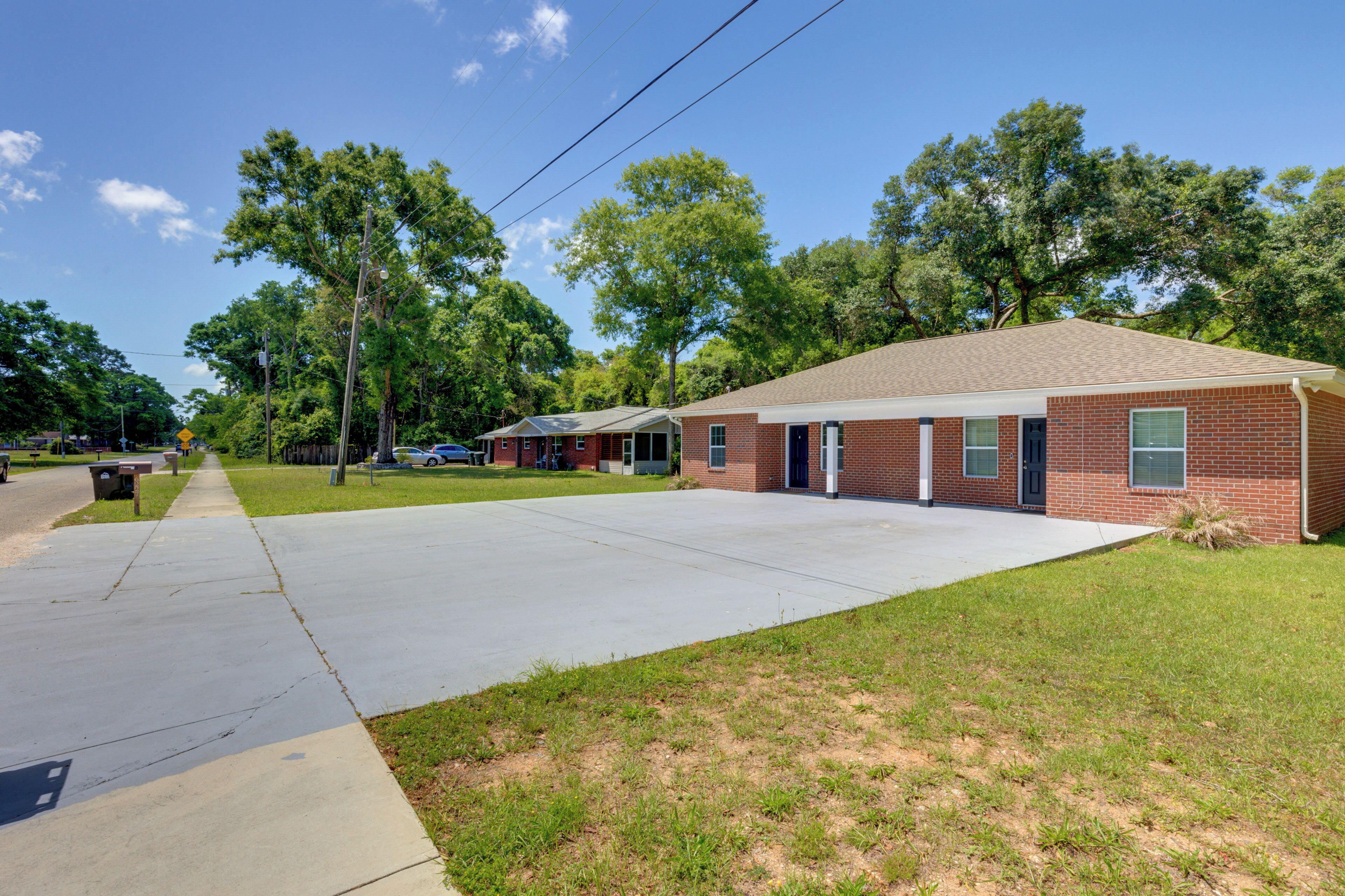A single-story brick building with a flat roof, a front parking area, and a sidewalk leading to a bench.