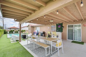 An outdoor patio with a pool, a barbecue area, and a covered seating area with a table and chairs. - Desert Hot Springs Home w/ Pool & Gas Grill! (Desert Hot Springs)