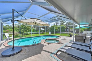 A covered outdoor swimming pool with lounge chairs and umbrellas.