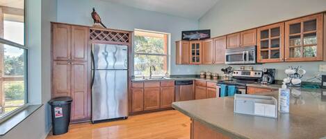 A kitchen with wooden cabinets, stainless steel appliances, and a large window.