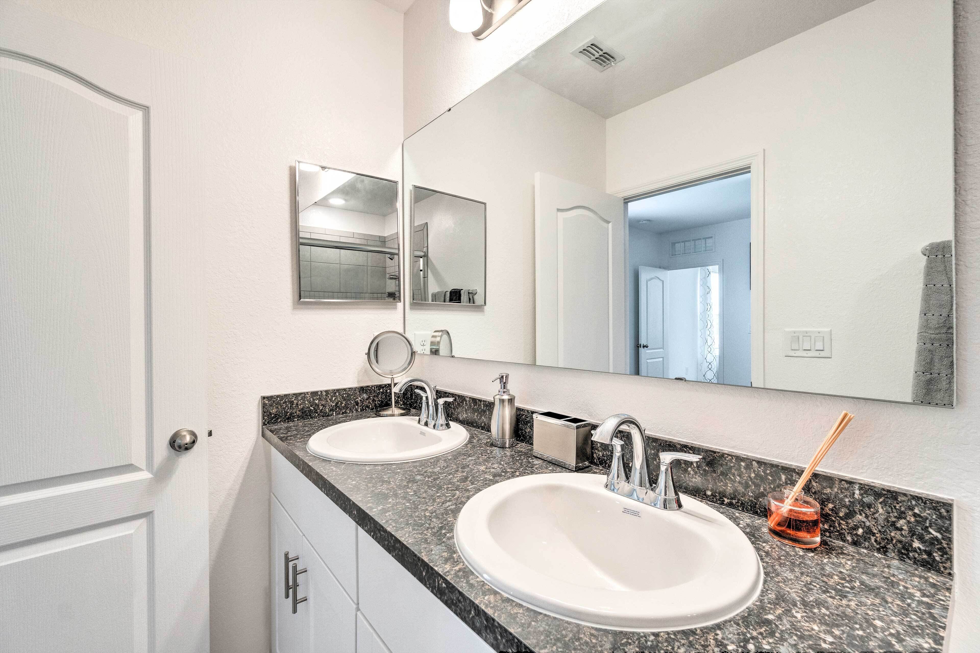 A bathroom with two sinks, a mirror, and a towel rack.