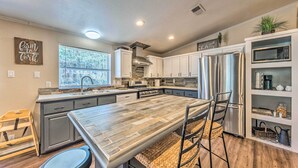 A modern kitchen with grey cabinets, stainless steel appliances, and a large island with bar stools.