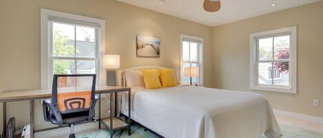 A bedroom with a bed, desk, chair, and ceiling fan.