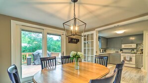 A dining area with a wooden table, six chairs, and a hanging light fixture. - Yarmouth Cottage w/ Grill & Yard, Walk to Beach (West Yarmouth)