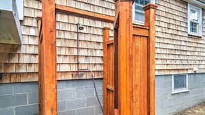 A wooden outdoor shower structure with a bench, a hose, and a window. - Yarmouth Cottage w/ Grill & Yard, Walk to Beach (West Yarmouth)