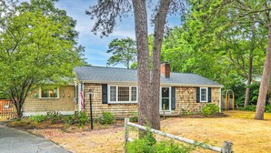 A single-story house with a brick chimney, a front porch, and a small garden area. - Yarmouth Cottage w/ Grill & Yard, Walk to Beach (West Yarmouth)