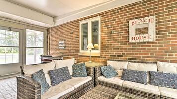 A cozy room with wicker furniture, a brick wall, and a sign that reads "The Beach House".