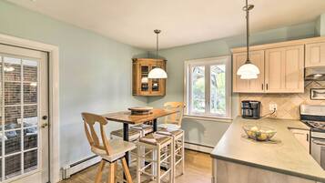 A kitchen with wooden chairs, a dining table, and pendant lights.