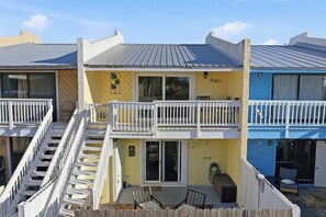 A two-story building with a balcony, a sliding door, and a small outdoor seating area. - Walk to Beach! The Sage PCB Family Getaway (Panama City Beach)