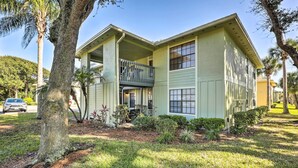 A two-story house with a balcony, surrounded by trees and a well-maintained lawn. - Sunny St Augustine Condo w/ Wifi - Walk to Beach! (St. Augustine)