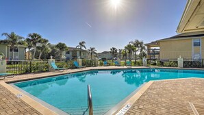 A swimming pool with a clear blue water, surrounded by lounge chairs and palm trees. - Sunny St Augustine Condo w/ Wifi - Walk to Beach! (St. Augustine)