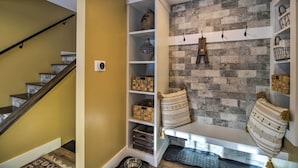 A staircase with a wooden railing, a white storage unit with shelves, and a textured brick wall. - Cozy Home w/ Sauna: Mins to Stowe Mountain Resort (Stowe)