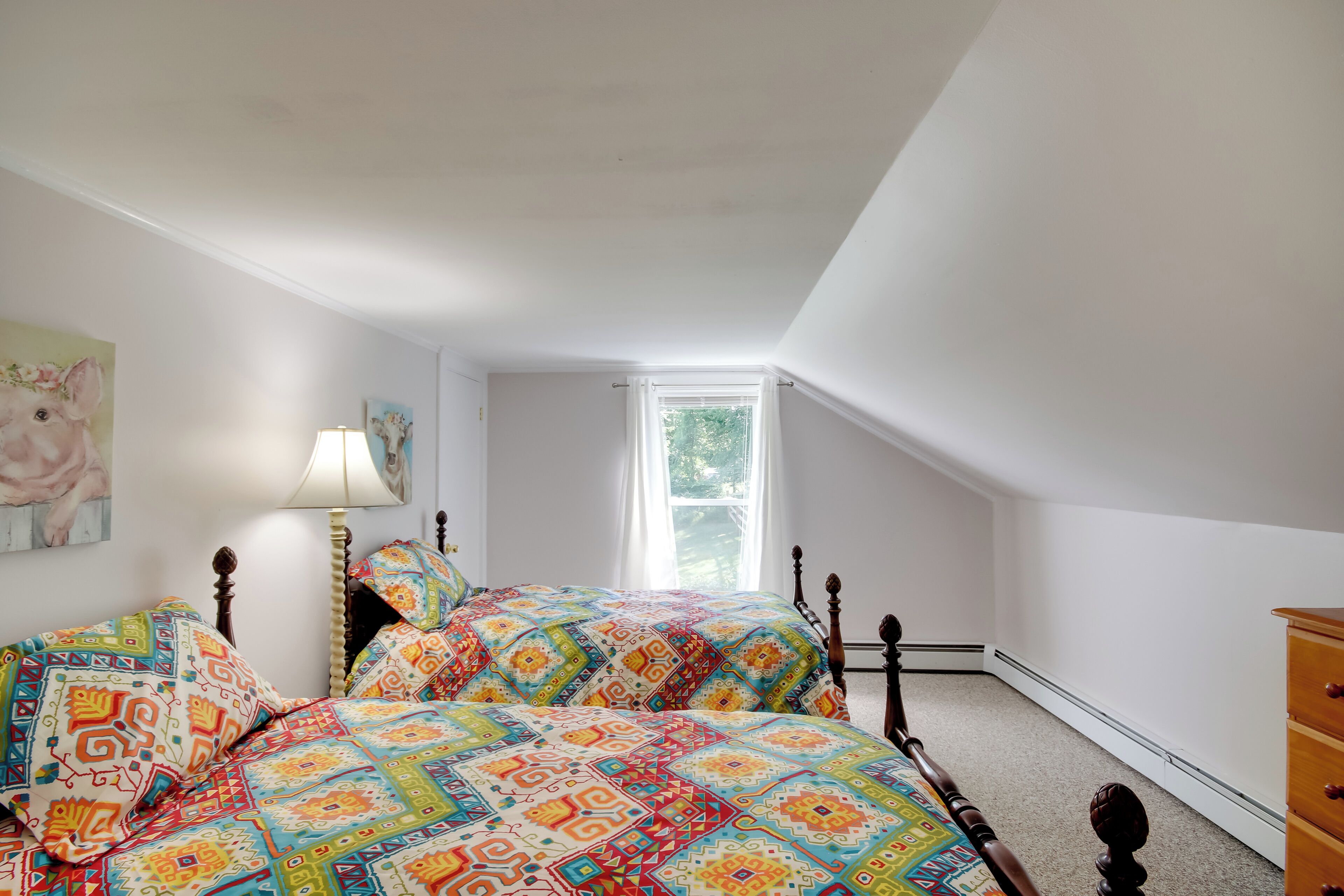 A bedroom with two beds, a dresser, and a window.