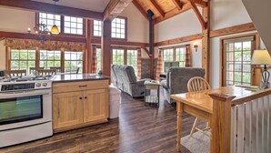 A spacious kitchen with wooden beams, large windows, and a dining area with a wooden table and chairs.