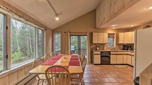 A spacious kitchen with wooden cabinets, a dining area with a long table and chairs, and large windows offering a view of the forest. - Dover Home: 7 Mi to Mount Snow Grand Summit Resort (East Dover)