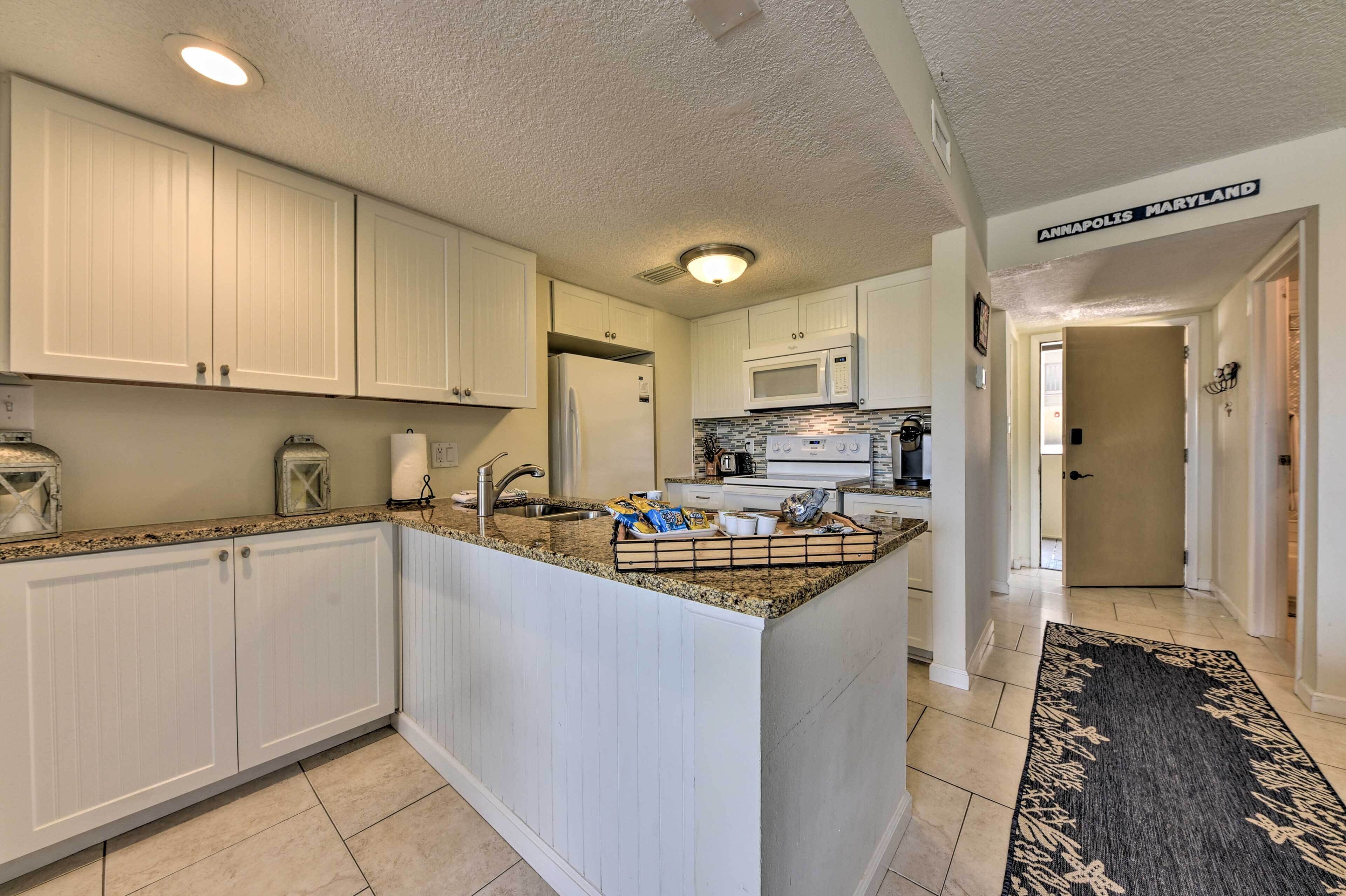 A kitchen with white cabinets, a granite countertop, and a microwave.