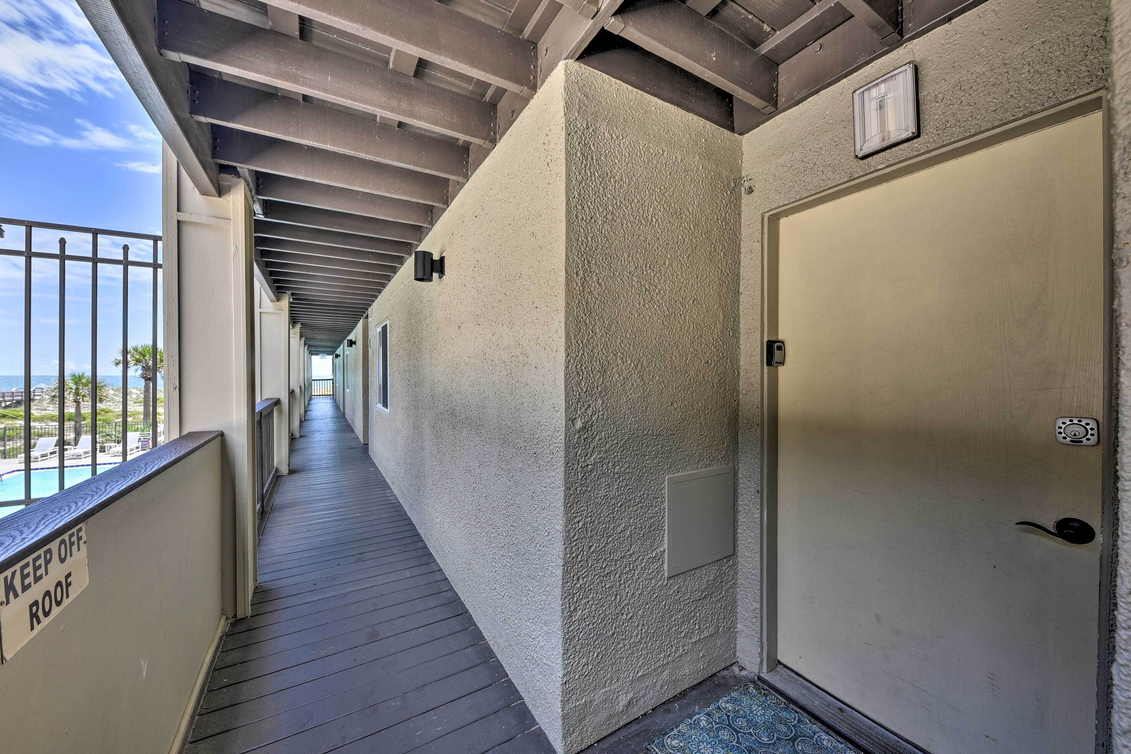 A corridor with a pool view, a door, and a 'KEEP OFF ROOF' sign.