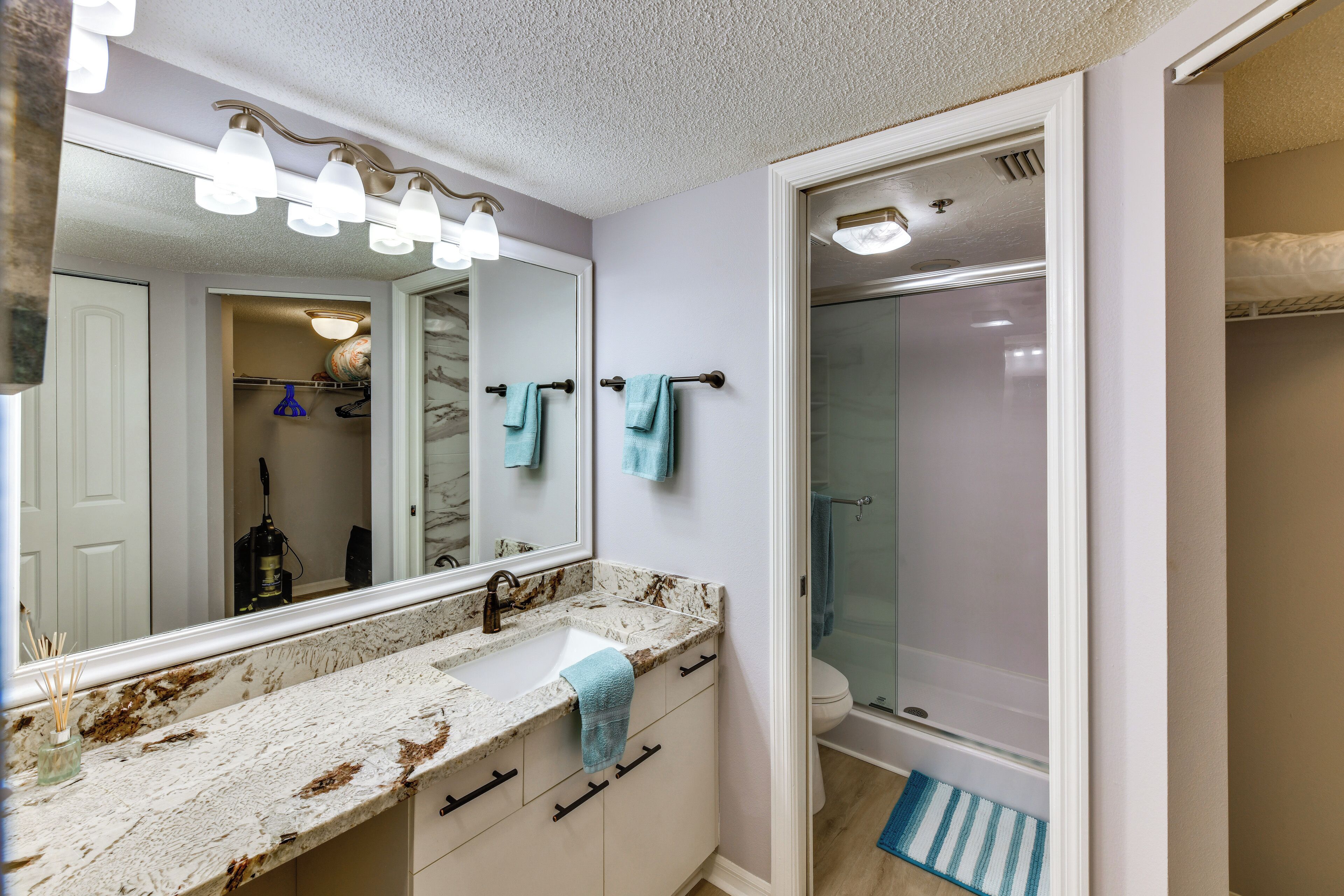 A bathroom with a white vanity, a large mirror, and a glass shower enclosure.
