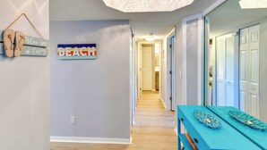 A hallway with a ceiling fan, a sign reading "BEACH", and a blue table with decorative items. - Walk to Beach: Home w/ Porch on Anna Maria Island! (Holmes Beach)