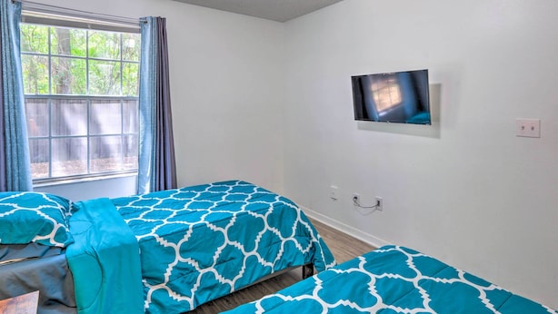 A bedroom with two beds, a TV on the wall, and a window with curtains. - Kissimmee Condo w/ Pool Access, 6 Mi to Disney! (Kissimmee)