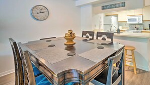 A modern kitchen with white cabinets, a microwave, and a refrigerator. There is a dining table with chairs and a clock on the wall. - Kissimmee Condo w/ Pool Access, 6 Mi to Disney! (Kissimmee)