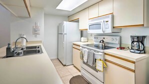 A compact kitchen with a refrigerator, microwave, stove, and sink. - Kissimmee Condo w/ Pool Access, 6 Mi to Disney! (Kissimmee)