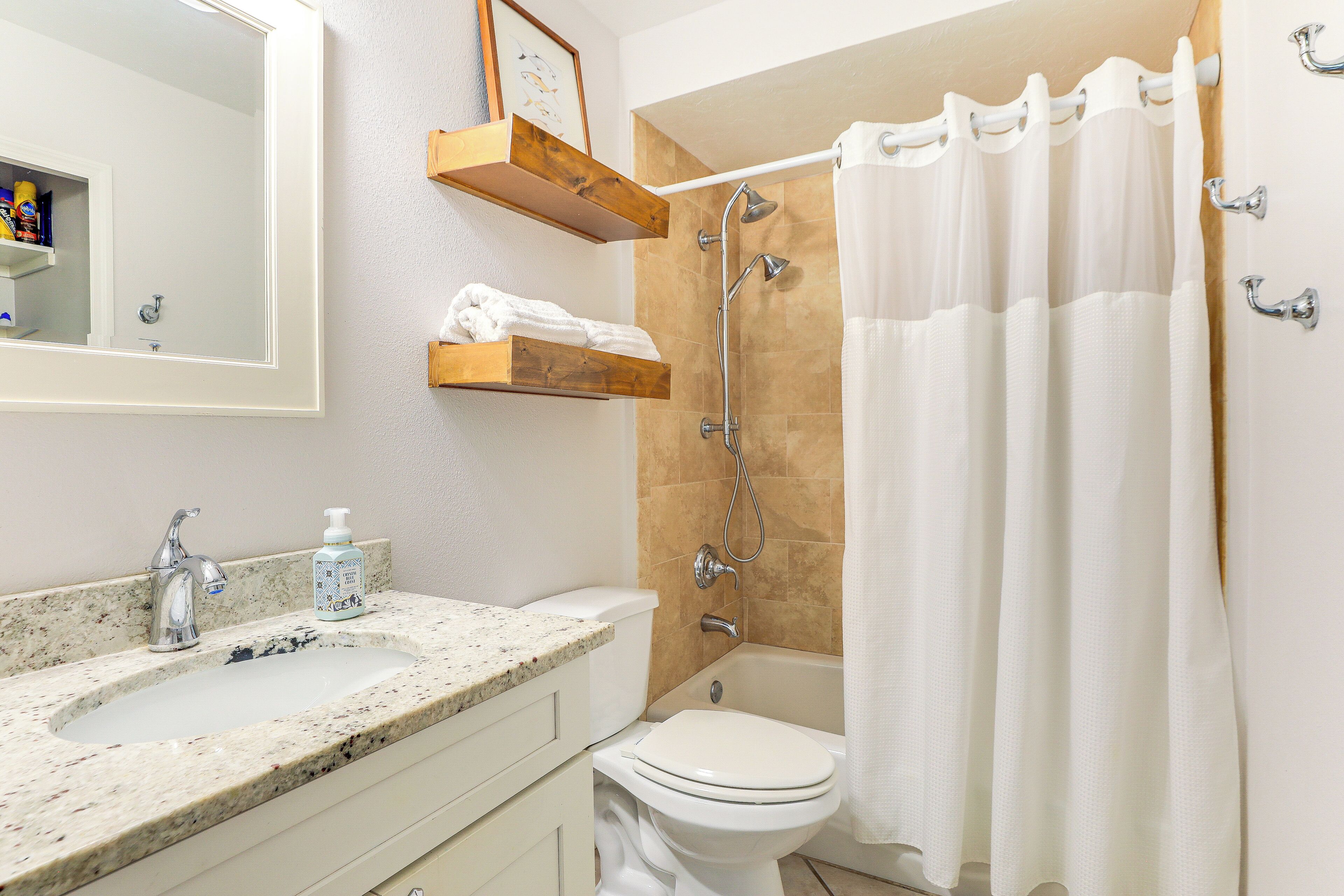 Une salle de bain équipée d’un lavabo, de toilettes, d’une douche et d’un miroir.