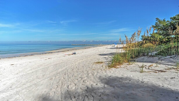 A wide sandy beach with a clear blue sky and calm sea. - Pelican Cove Condo at Bradenton Beach w/ Pool! (Bradenton Beach)