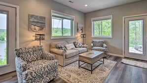 A living room with a beige sofa, patterned armchairs, a coffee table, and artwork on the walls. - Lake Views, Fire Pit! Blue Cabin Ozarks Getaway (Camdenton)