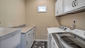 A laundry room with a washing machine, dryer, and stacked cabinets. - Lake Views, Fire Pit! Blue Cabin Ozarks Getaway (Camdenton)