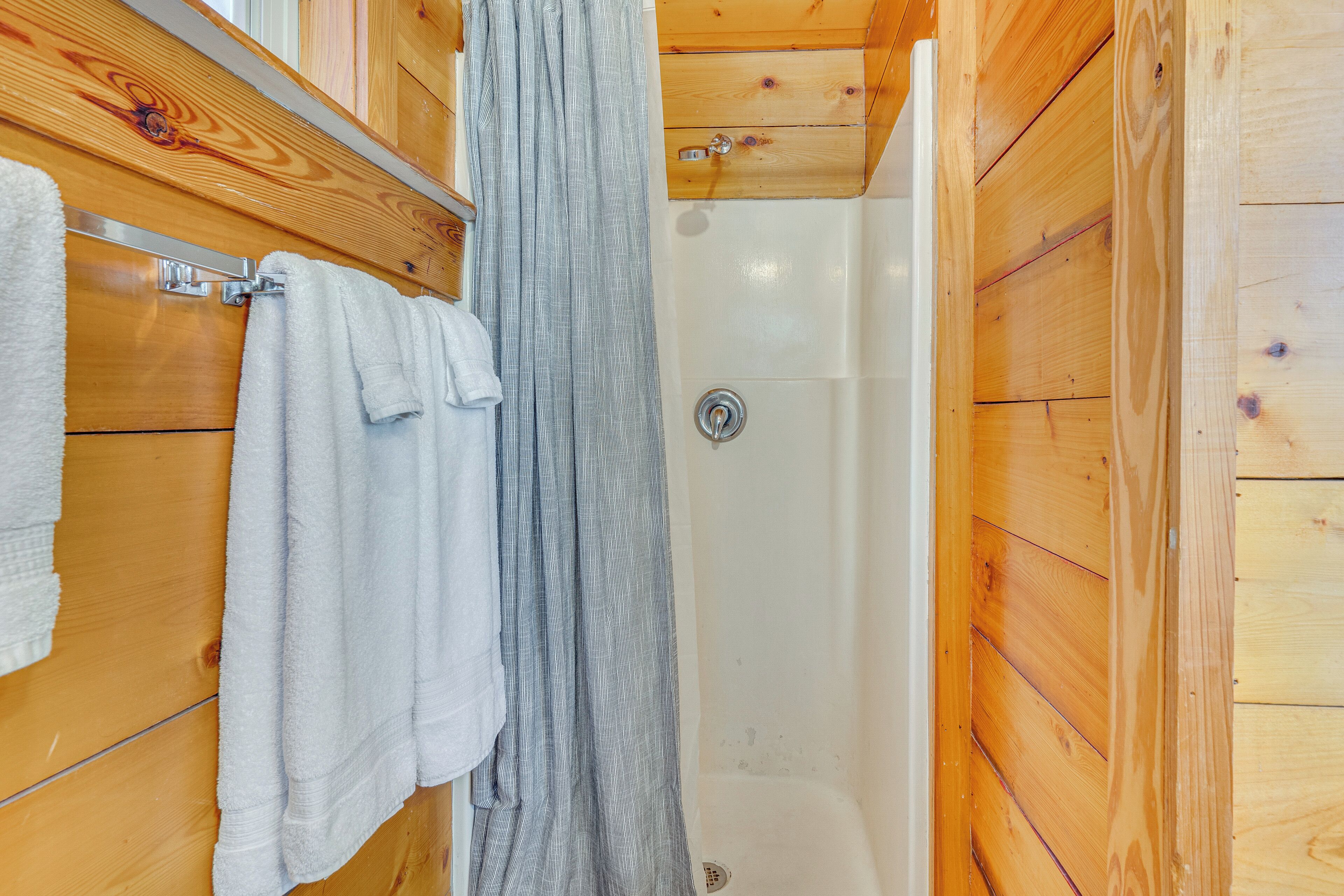 A wooden bathroom with a shower, a towel rack, and a wooden cabinet.