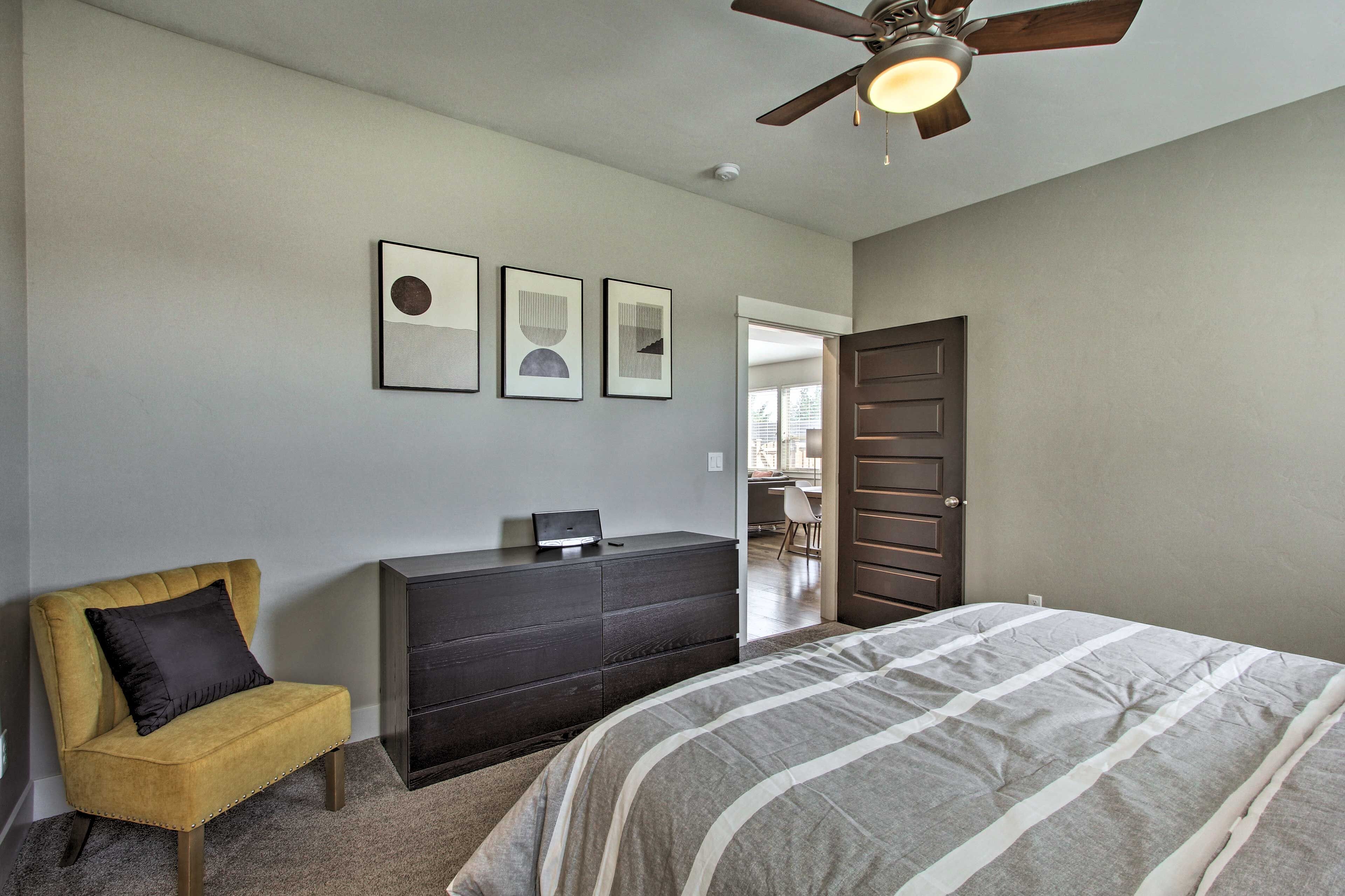 A bedroom with a bed, a dresser, a chair, and a ceiling fan.
