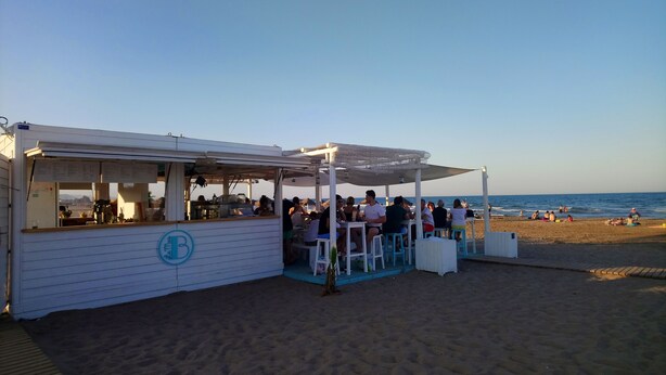 A beachside café with outdoor seating and a view of the ocean. - Atico-loft Mompó. Lujo Marítimo (València)