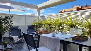 An outdoor patio with a table set for two, surrounded by chairs and potted plants. - Atico-loft Mompó. Lujo Marítimo (València)