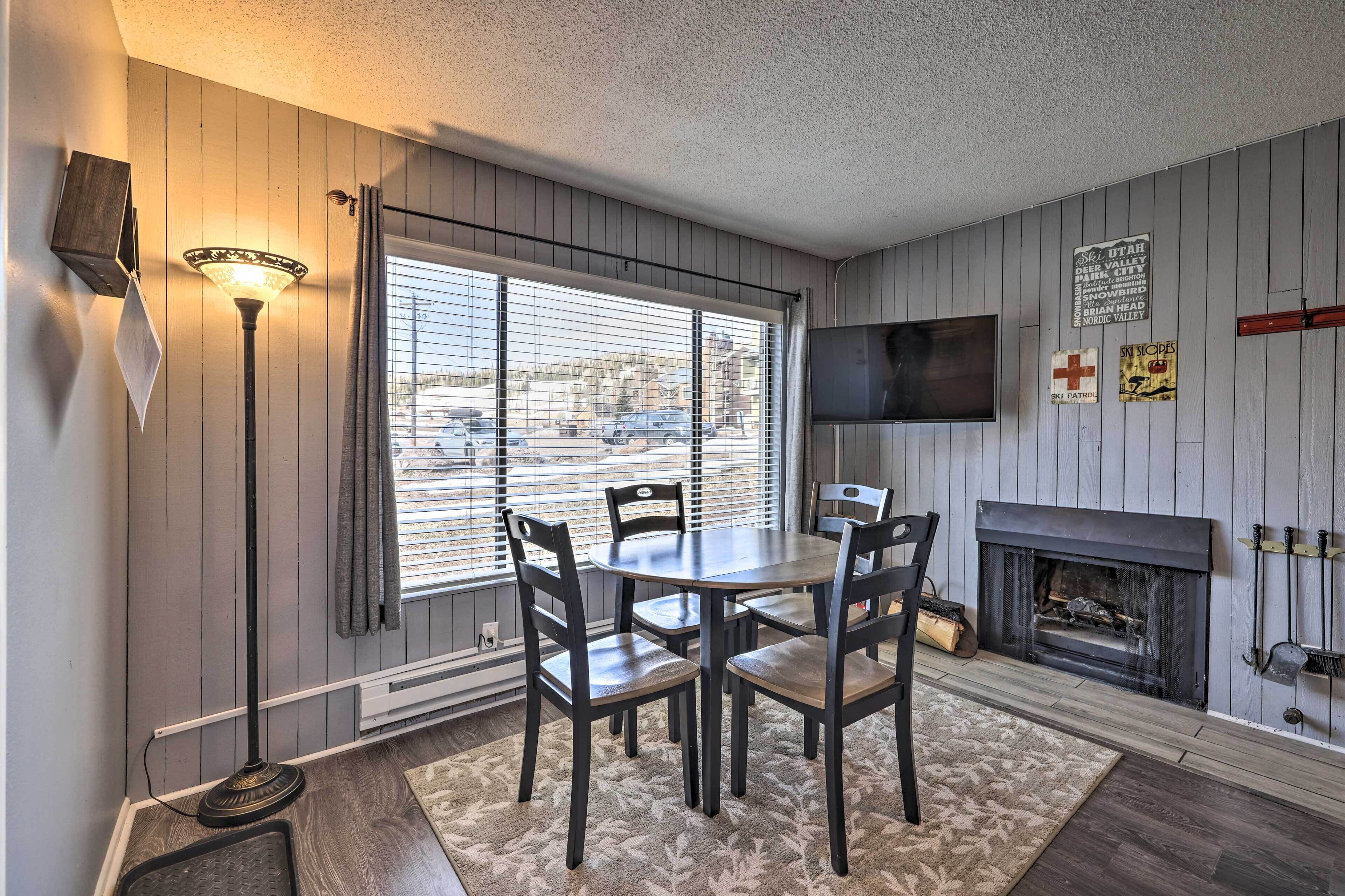 A dining area with a table and chairs, a fireplace, and a television mounted on the wall.