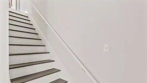 A staircase with white walls and a handrail.