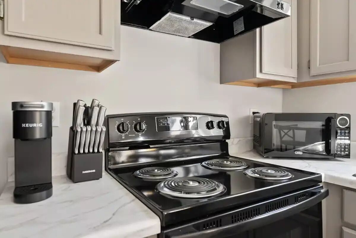 A modern kitchen with a black stove, a coffee maker, and a microwave.