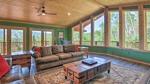 A spacious living room with a leather sofa, a wooden coffee table, and large windows offering a view of the outdoors. - < 1 Mi to Brian Head Resort: Mtn-view Gem w/ Deck (Brian Head)