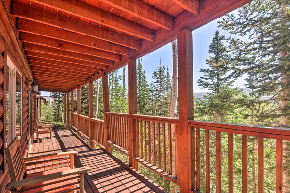 Un pontile di legno con panchine, circondato da alberi alti e un cielo sereno.