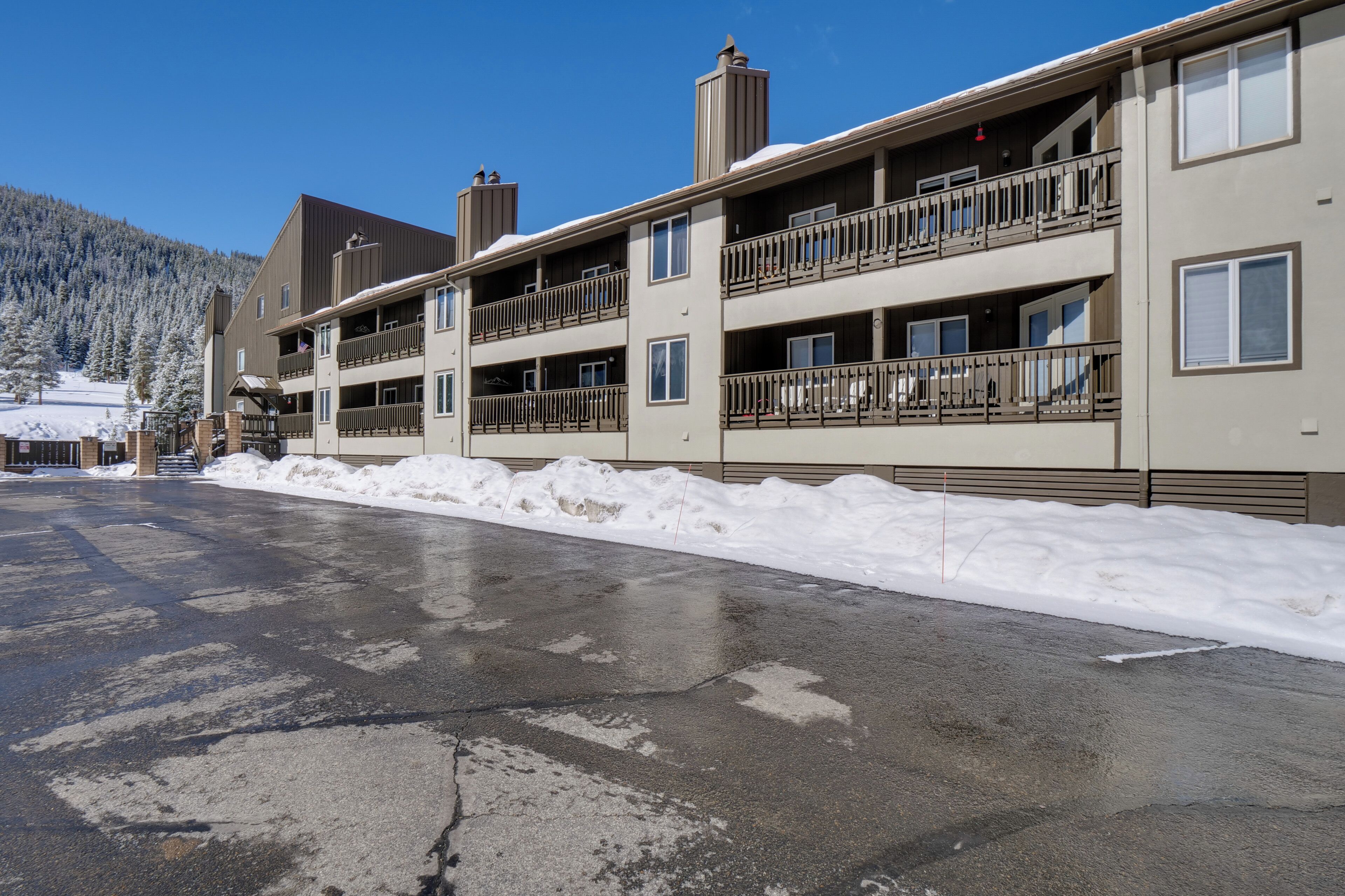 A multi-story hotel with balconies, a snow-covered ground, and a mountain backdrop.