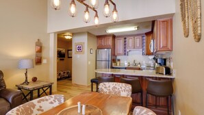 Una cocina moderna con armarios de madera, una isla central y un comedor con mesa y sillas de madera.