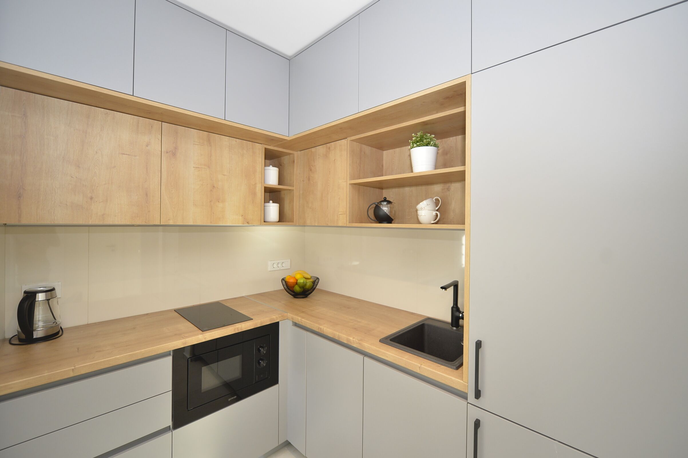 Una cocina moderna con armarios de madera, encimera negra, horno empotrado y un fregadero.