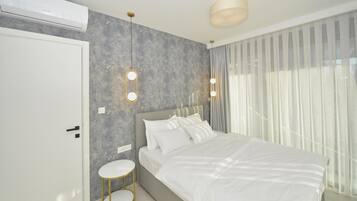A modern bedroom with a large bed, a round side table, and a wall-mounted air conditioner.