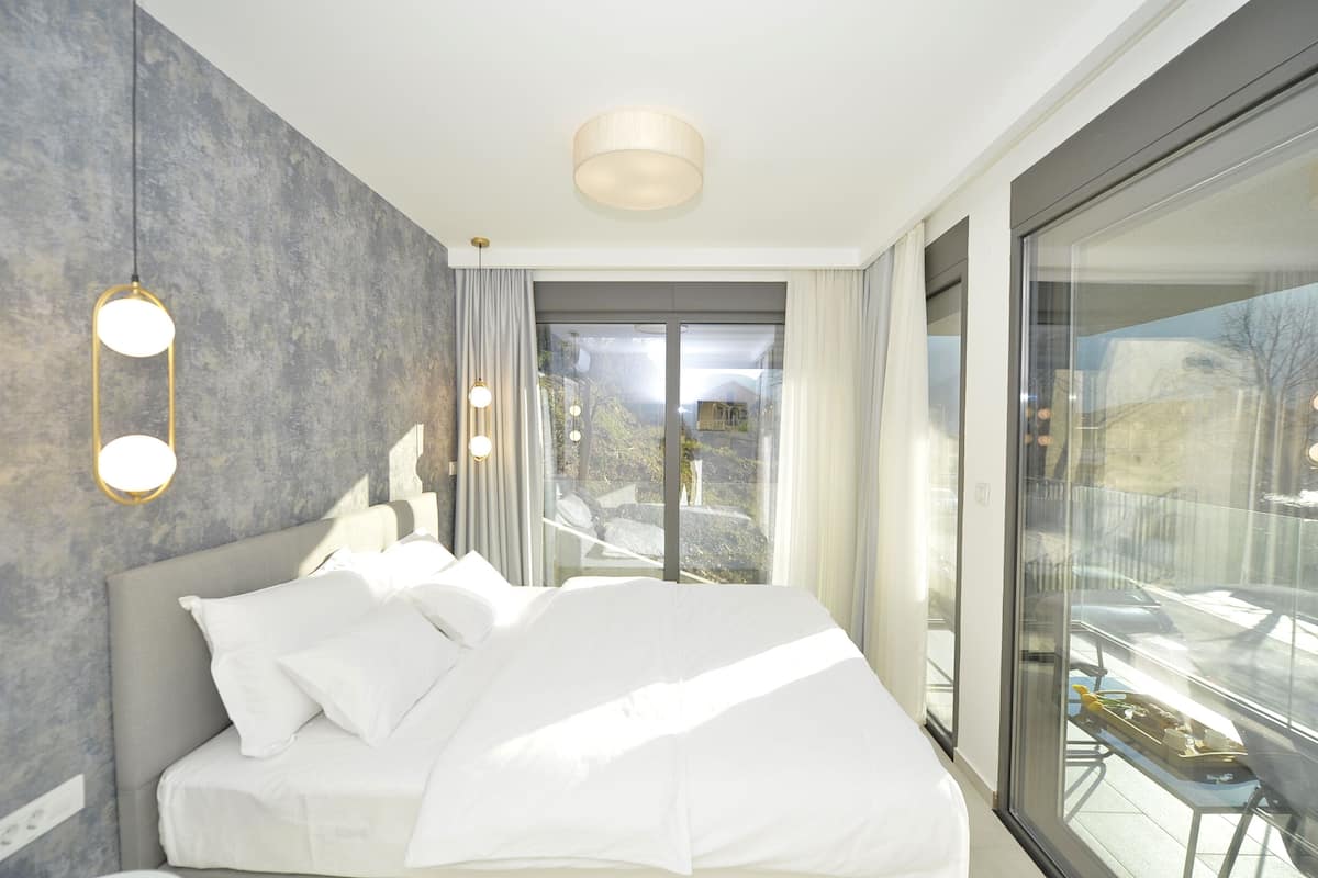 Habitación de hotel moderna con una cama grande, vistas al exterior a través de ventanales de piso a techo y una decoración minimalista.