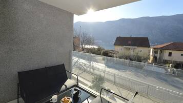 A balcony with a table, chairs, and a view of a mountain and lake.